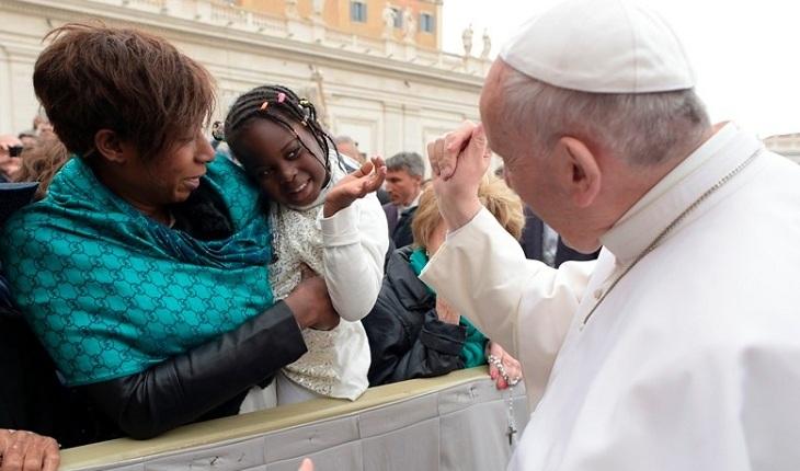 Na imagem, o papa francisco interage com uma menina que estÃ¡ no colo da mÃ£e acenando. Papa Francisco com crianÃ§as.