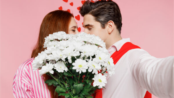 Casal se beija atrás de um buquê de flores
