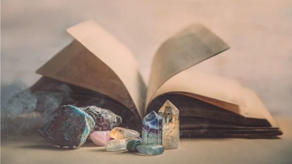 Imagens ilustrativas de um livro de rituais e alguns cristais ao redor