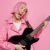 mulher tocando guitarra em fundo rosa