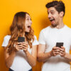 Homem e mulher felizes com celular na mão