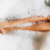 Pernas de mulher em espuma de banho. Vista superior.