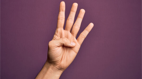 Mão de jovem, mostrando os dedos sobre fundo roxo isolado, contando o número 4, mostrando quatro dedos.