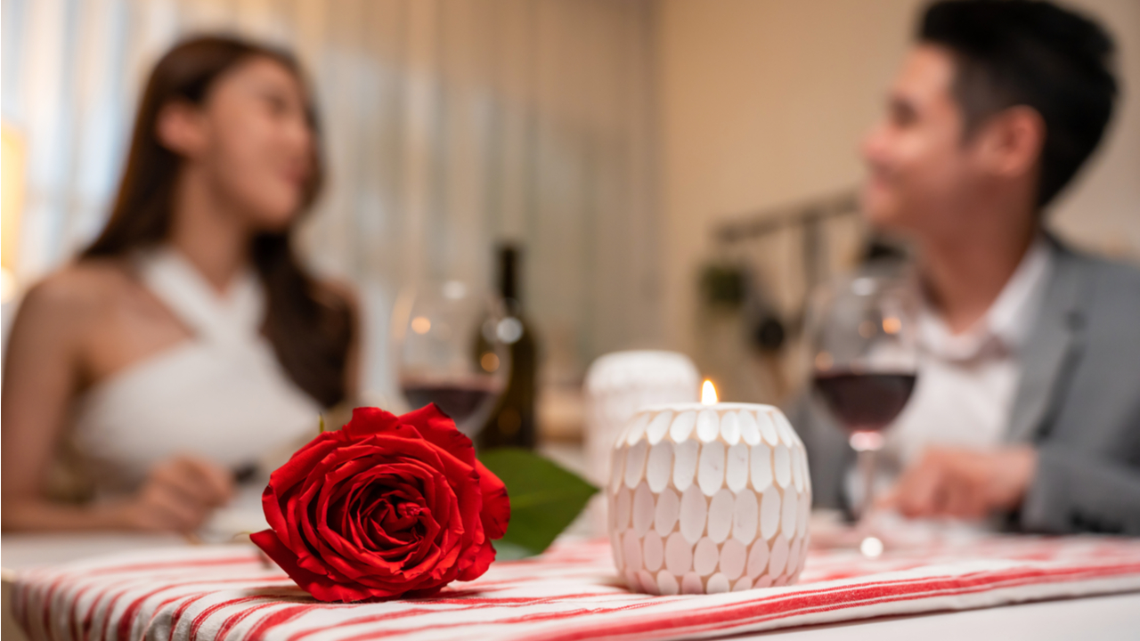 casal jantando com rosa vermelha e velas