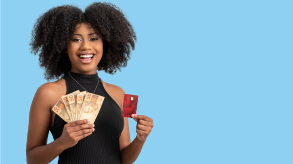 mulher negra segurando dinheiro e cartão de crédito em fundo azul