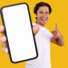 homem feliz segurando um celular em fundo amarelo