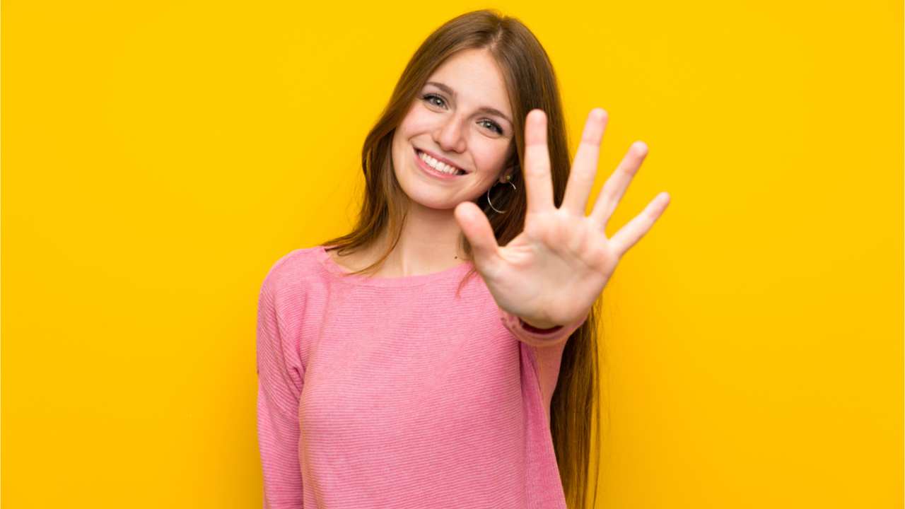 Jovem mulher com cabelo comprido sobre parede amarela isolada contando 5 com os dedos.