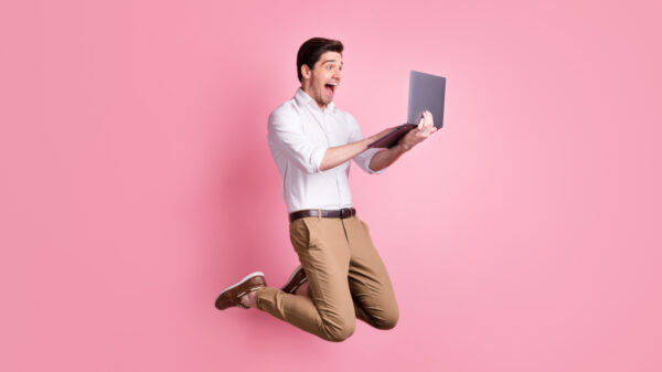homem segurando um notebook com fundo rosa