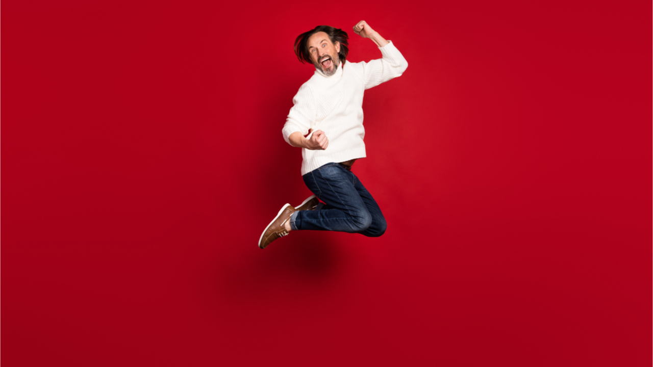 Foto do tamanho do corpo inteiro de um homem pulando isolado em fundo de cor vermelha.