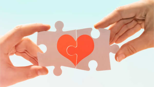 Um homem e uma mulher conectando peças de um quebra-cabeça com a imagem de um coração. Compatibilidade entre homem e mulher.