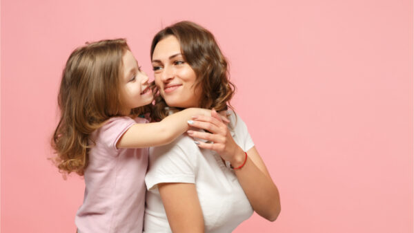 Mulher com roupas leves se divertindo com uma linda criança. Mãe e filha isoladas no fundo da parede rosa pastel, retrato de estúdio. Família de amor do dia das crianças; conceito de infância.