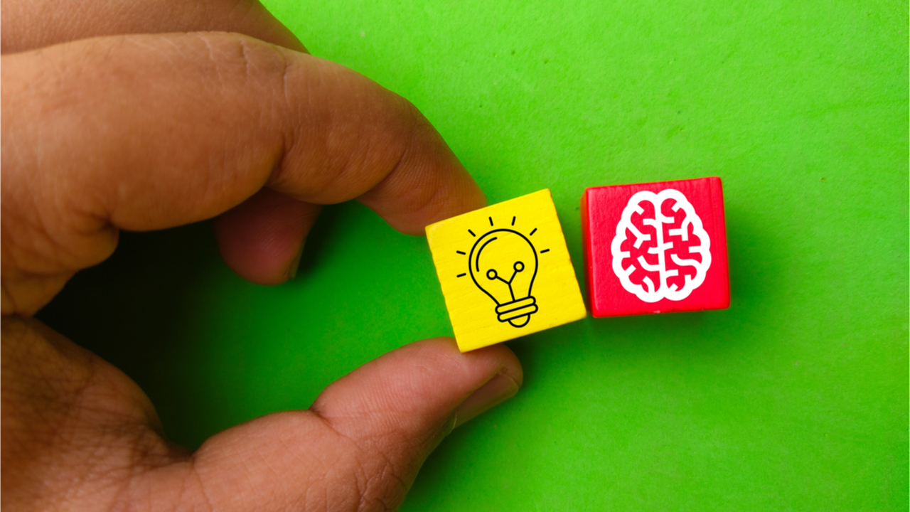 Mão segurando cubos coloridos com ícones de lâmpada e cérebro. Conceito de inovação.