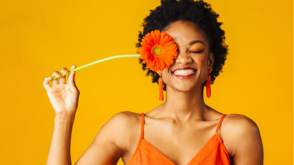 mulher feliz com uma flor na altura dos olhos