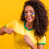 torcedora do brasil vestindo camisa verde e amarela em fundo também amarelo