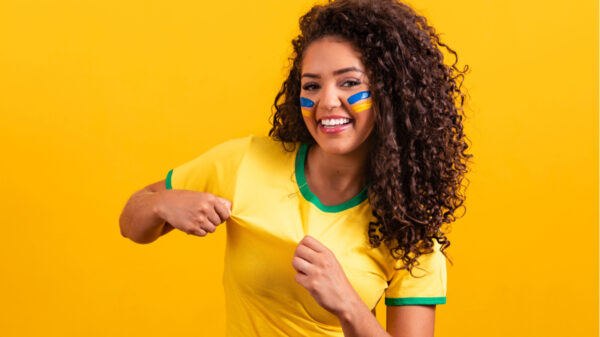 torcedora do brasil vestindo camisa verde e amarela em fundo também amarelo