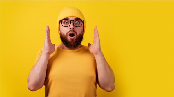 Homem de óculos surpreso sobre fundo amarelo.
