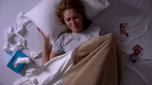 mulher chorando na cama ao lado de uma foto com o ex namorado