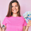 mulher segurando dinheiro em fundo rosa