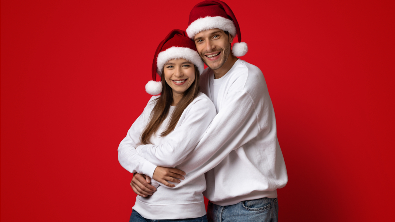 casal com touca natalina em fundo vermelho