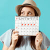 mulher segurando um calendário e usando um chapéu em fundo azul