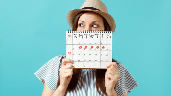 mulher segurando um calendário e usando um chapéu em fundo azul