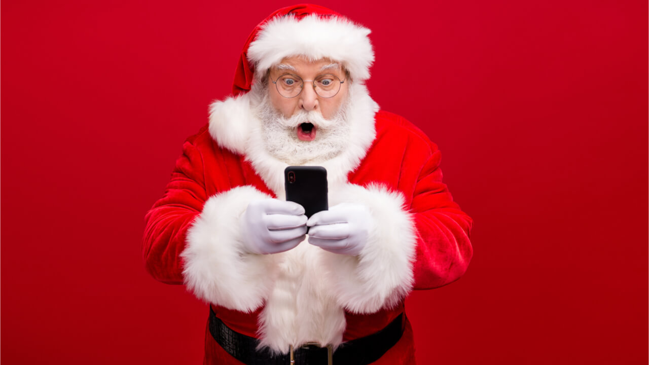Retrato de homem vestido de Papai Noel usando celular, isolado sobre fundo de cor vermelha.