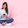 Mulher jovem isolada em fundo rosa no celular.