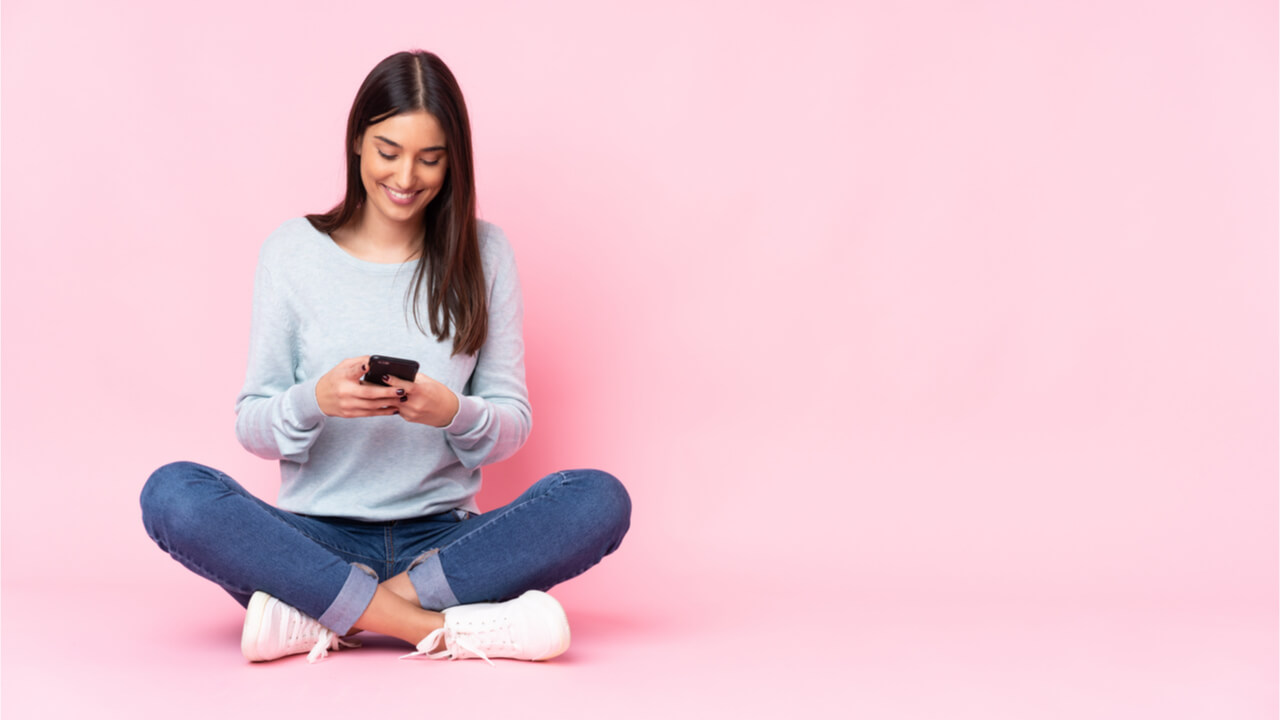 Mulher jovem isolada em fundo rosa no celular.