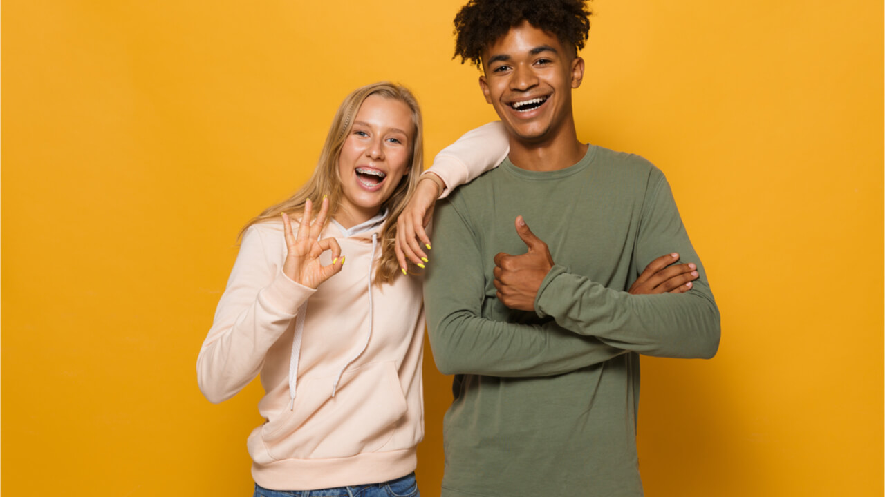 Foto de pessoas alegres, homem e mulher de cerca de 16 a 18 anos, isolados sobre fundo amarelo.