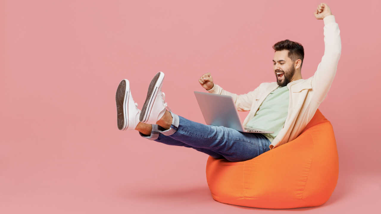 homem com um computador no colo feliz