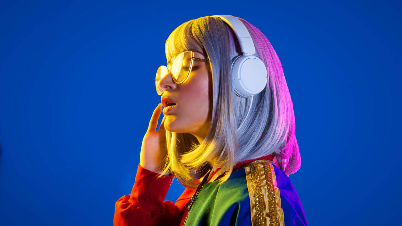 Retrato de uma mulher ouvindo música em fundo colorido.