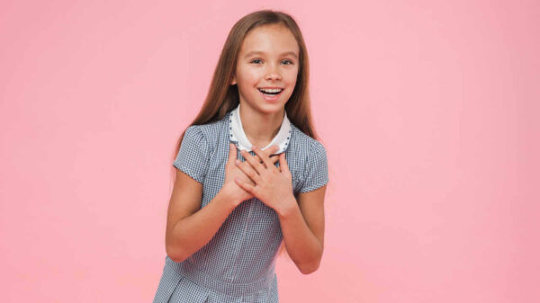 Estudante feliz e emotiva. Jovem pré-adolescente mostrando emoções positivas, isolada em fundo rosa.