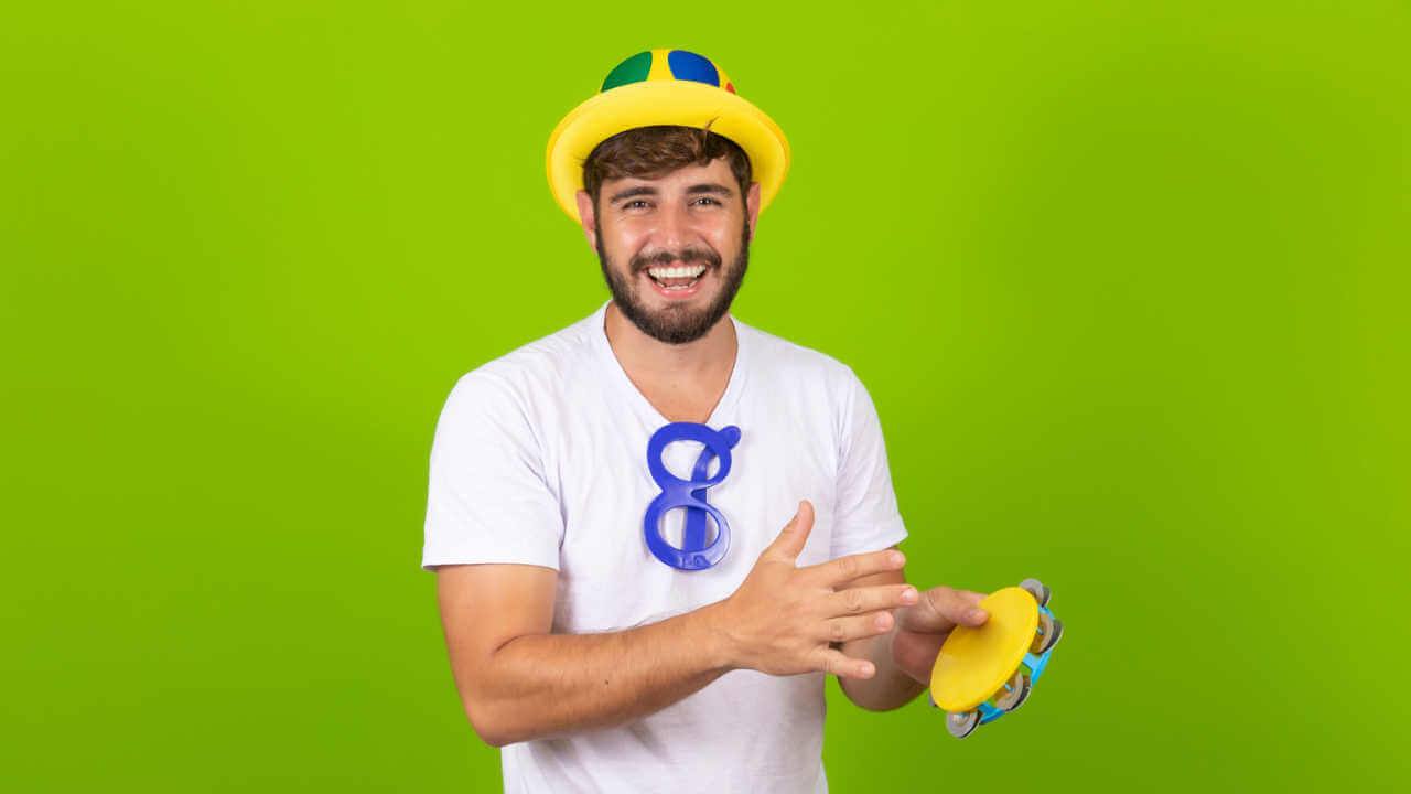 Homem vestido para o carnaval com um pandeiro nas mãos. Jovem vestido com fantasia de carnaval tocando pandeiro na festa de carnaval.