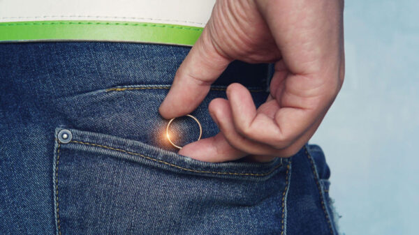 Foto da mão de um jovem colocando ou um anel de casamento no bolso da calça jeans. Conceito de infidelidade. Homem tirando anel antes da infidelidade.