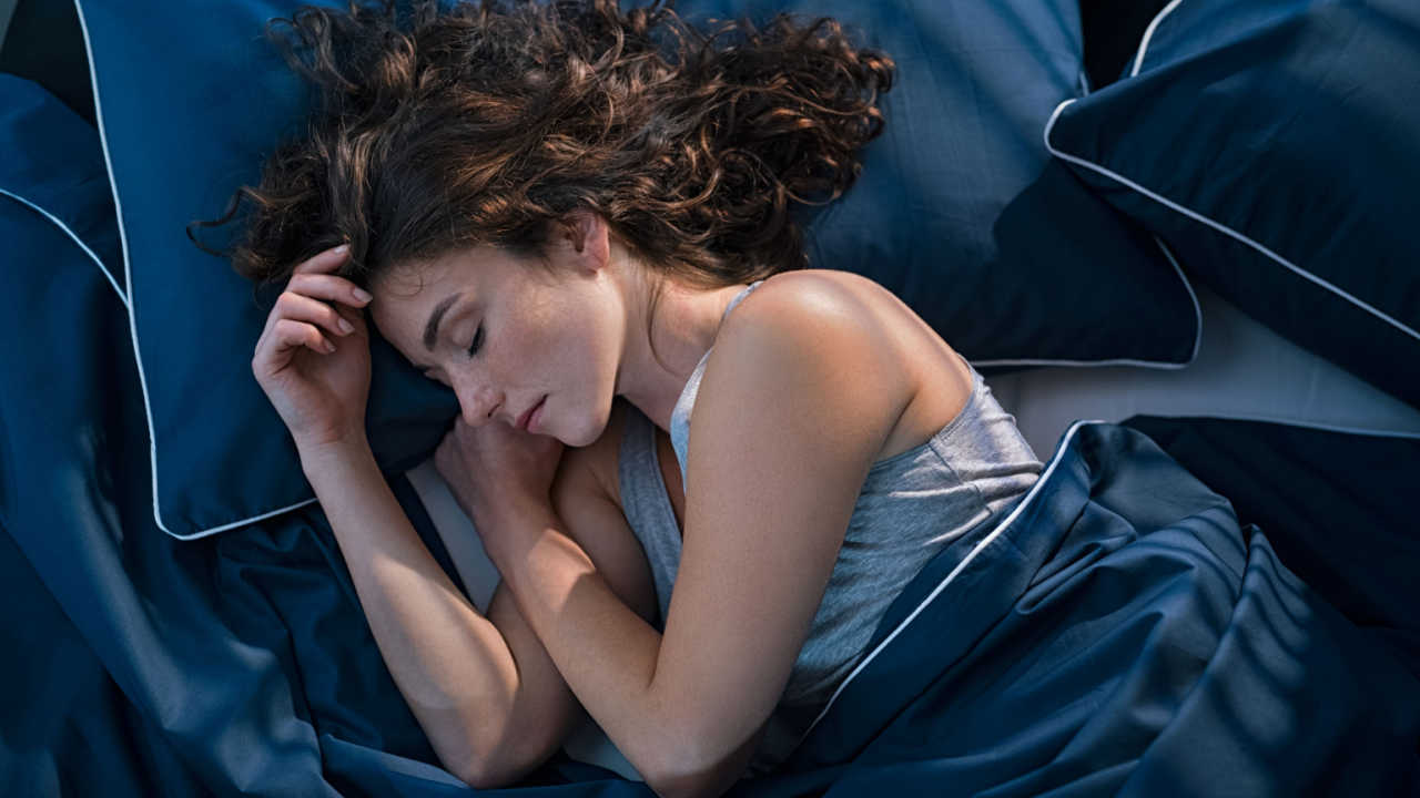 mulher dormindo em lençóis azul escuro