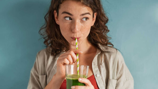 mulher bebendo suco verde em fundo azul