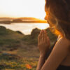 Mulher orando sozinha ao nascer do sol. Fundo de natureza. Conceito espiritual e emocional. Sensibilidade à natureza.
