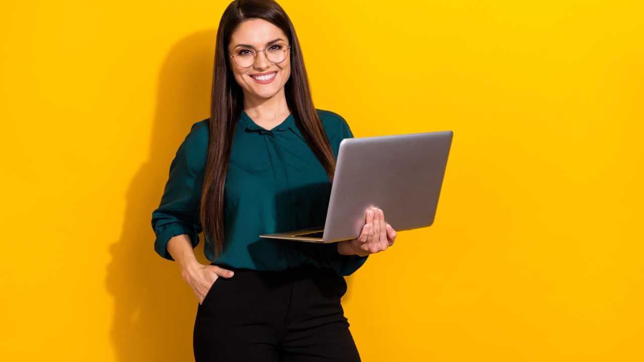 Foto de uma jovem usando laptop, isolada sobre um fundo de cor amarela.