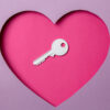 Chave localizada em um papel rosa em forma de coração. Tudo ao redor é roxo. Amor. Segurança.