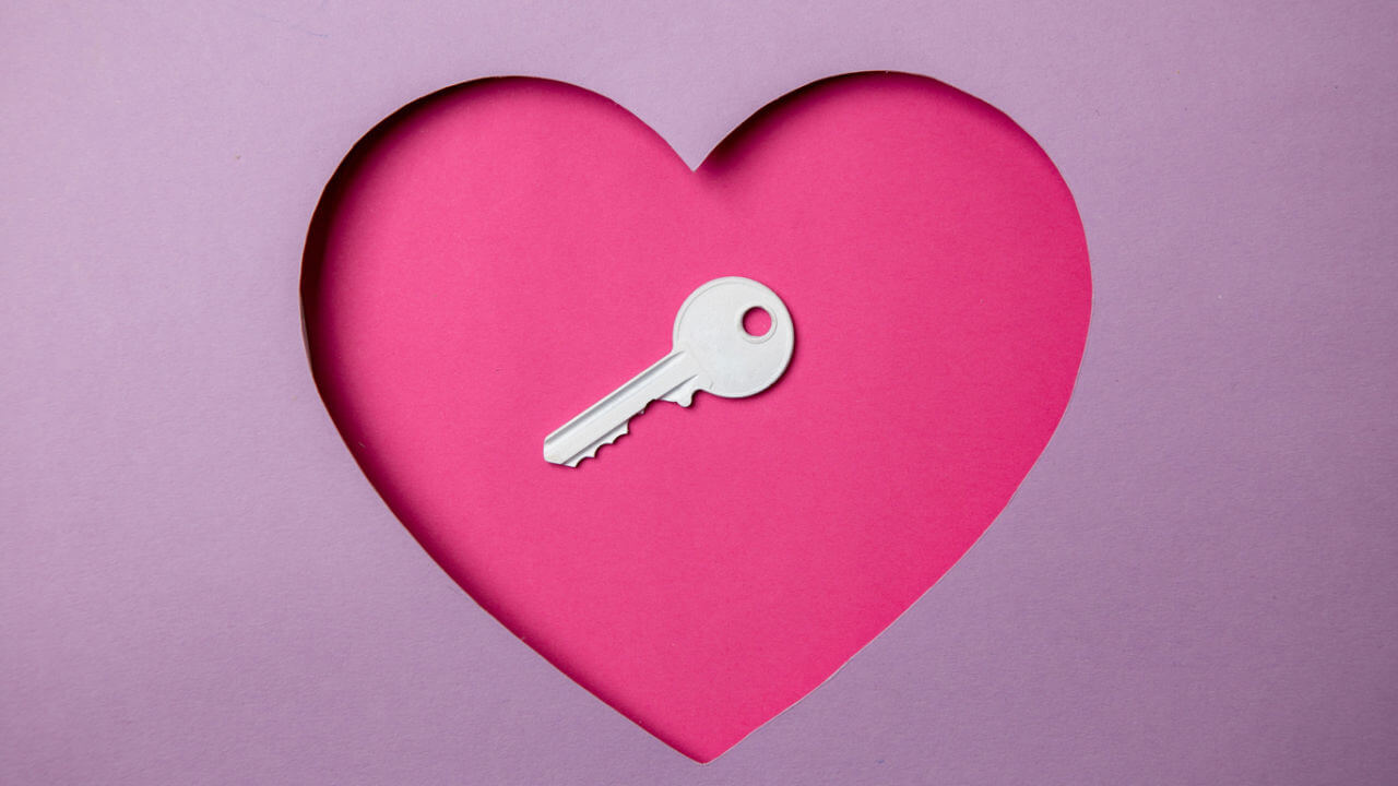 Chave localizada em um papel rosa em forma de coração. Tudo ao redor é roxo. Amor. Segurança.