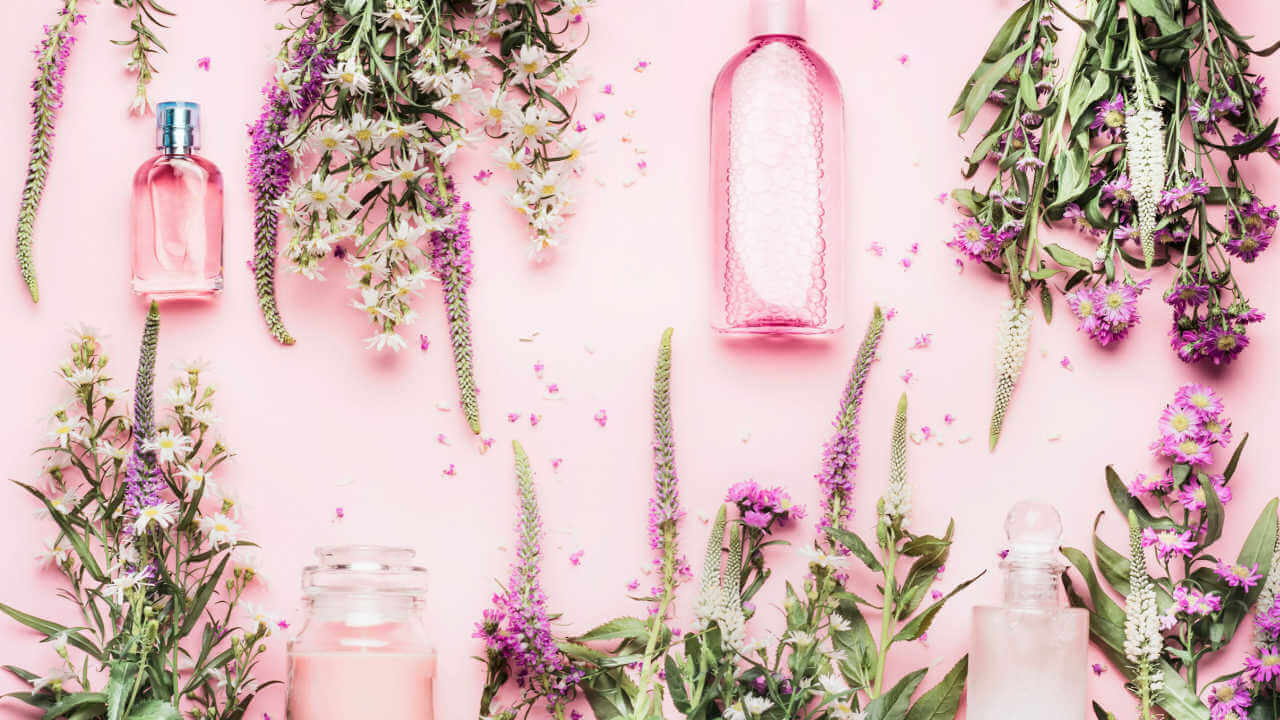 Produtos e cosméticos naturais em garrafas, e ervas frescas e flores em um fundo rosa. Vista superior. Conceito de banho de ervas.
