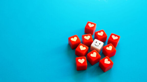 Um cubo com dois olhos e uma boca sorrindo, rodeado por cubos com coração. Conceito de amor, cuidado e empatia.