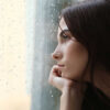 mulher olhando para a janela num dia chuvoso