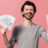 homem segurando notas de dinheiro em fundo rosa