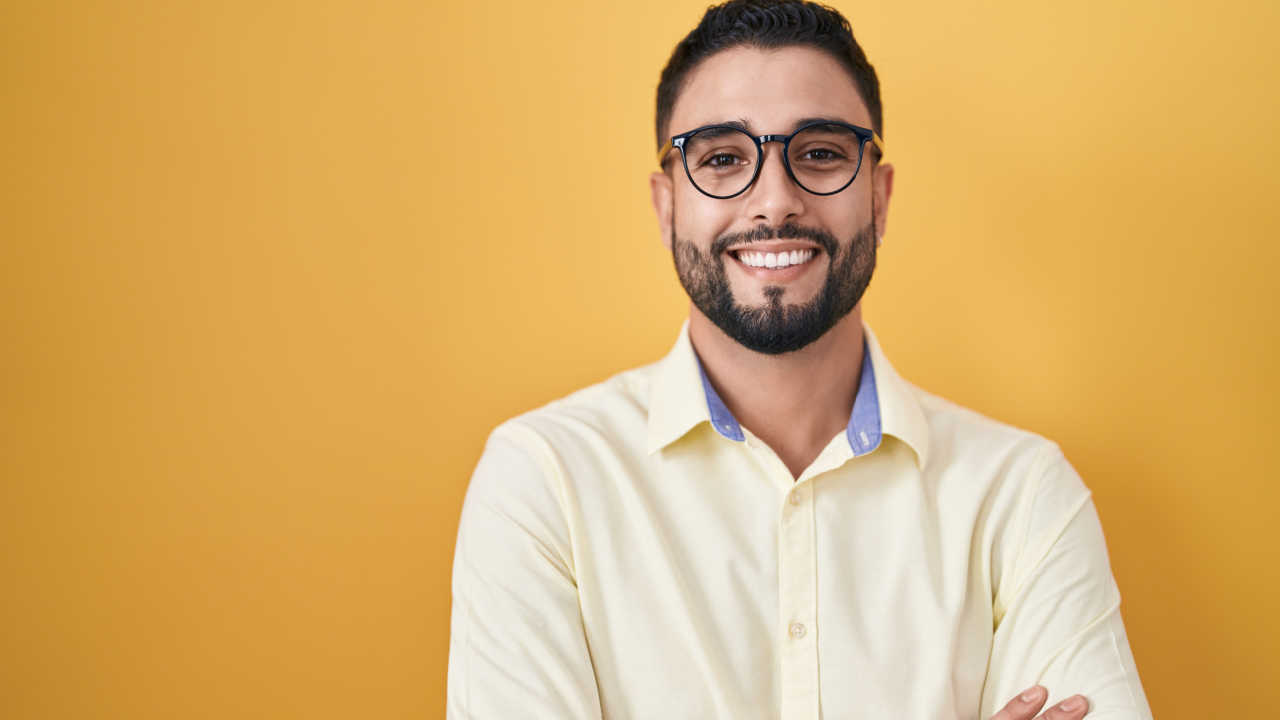 homem com óculos sorrindo em fundo laranja