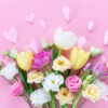 Buquê de flores da primavera e corações de papel na mesa rosa pastel para Dia das Mães.