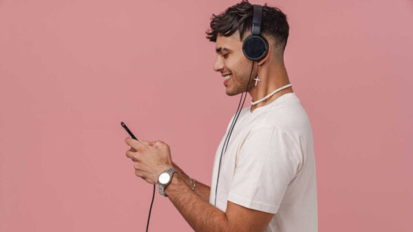 homem ouvindo música com fone de ouvido em fundo rosa