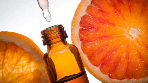 vidro de óleo essencial com uma laranja ao fundo
