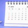 Calendário de mesa mensal de junho de 2023, e lápis, sobre fundo roxo.