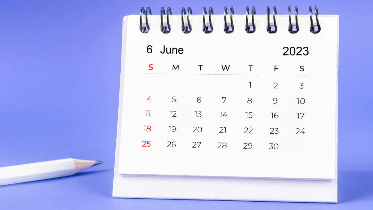 Calendário de mesa mensal de junho de 2023, e lápis, sobre fundo roxo.